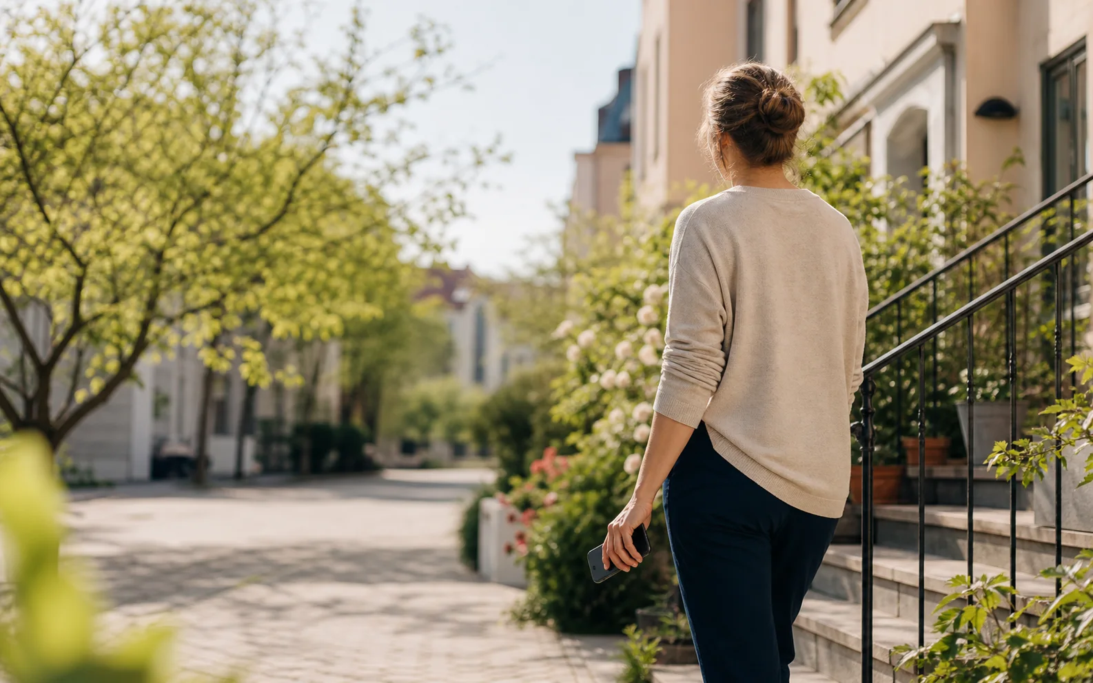 Person som promenerar genom ett svenskt bostadskvarter med telefonen i handen